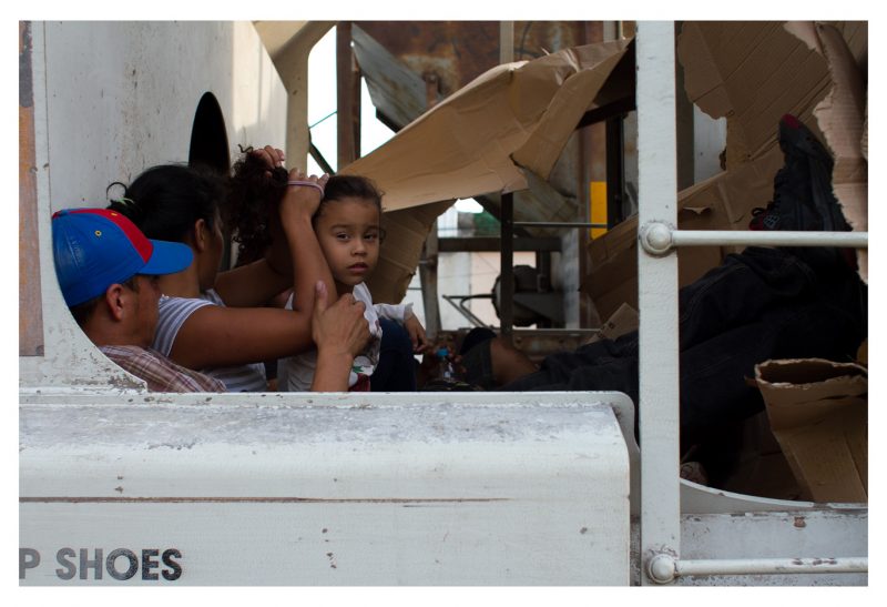 Arriaga, Chiapas. 6 May 2014. While riding the train, a Honduran child turns her gaze at me as she gets her hair done. She is from San Pedro Sula, the most violent city in the world, where hope is non-existent and death, confused with dust, seizes the souls of “guiros”, as kids are called in Honduras. Faced with the choice of either becoming paid assassins for local gangs, or killed because of refusing to do so, children flee their country. Sending an unaccompanied child from Honduras to the border of the United States can cost up to $5,000 USD. This cost includes travelling in luxury buses through Mexico, and the payments made to cartels and Mexican authorities in order to cross the country without risking detention.